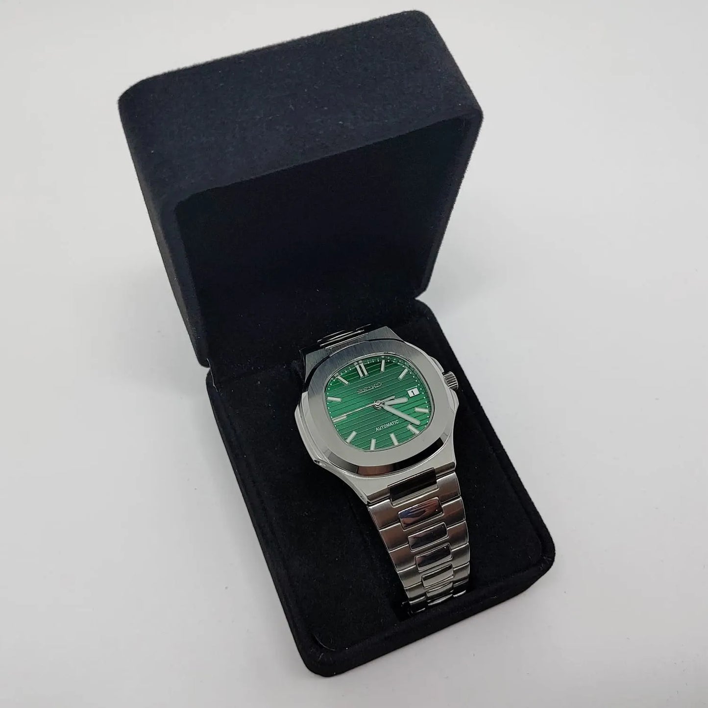 Stainless steel 40mm watch with green dial and silver hour markers on metal bracelet in black velvet box.