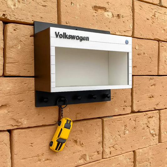 White and black Volkswagen wall-mounted key hook rack with three black hooks and a yellow car keychain hanging on one hook.