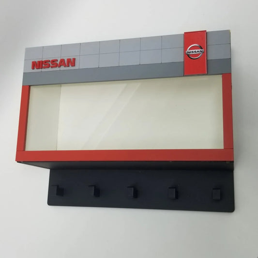 Nissan wall key hook rack designed like a showroom facade with five black hooks and Nissan logo panel above.