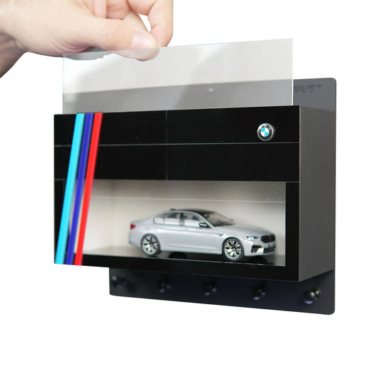 Black BMW wall key hook rack with red, blue, and light blue stripes, scale model silver car inside, transparent cover lifted .
