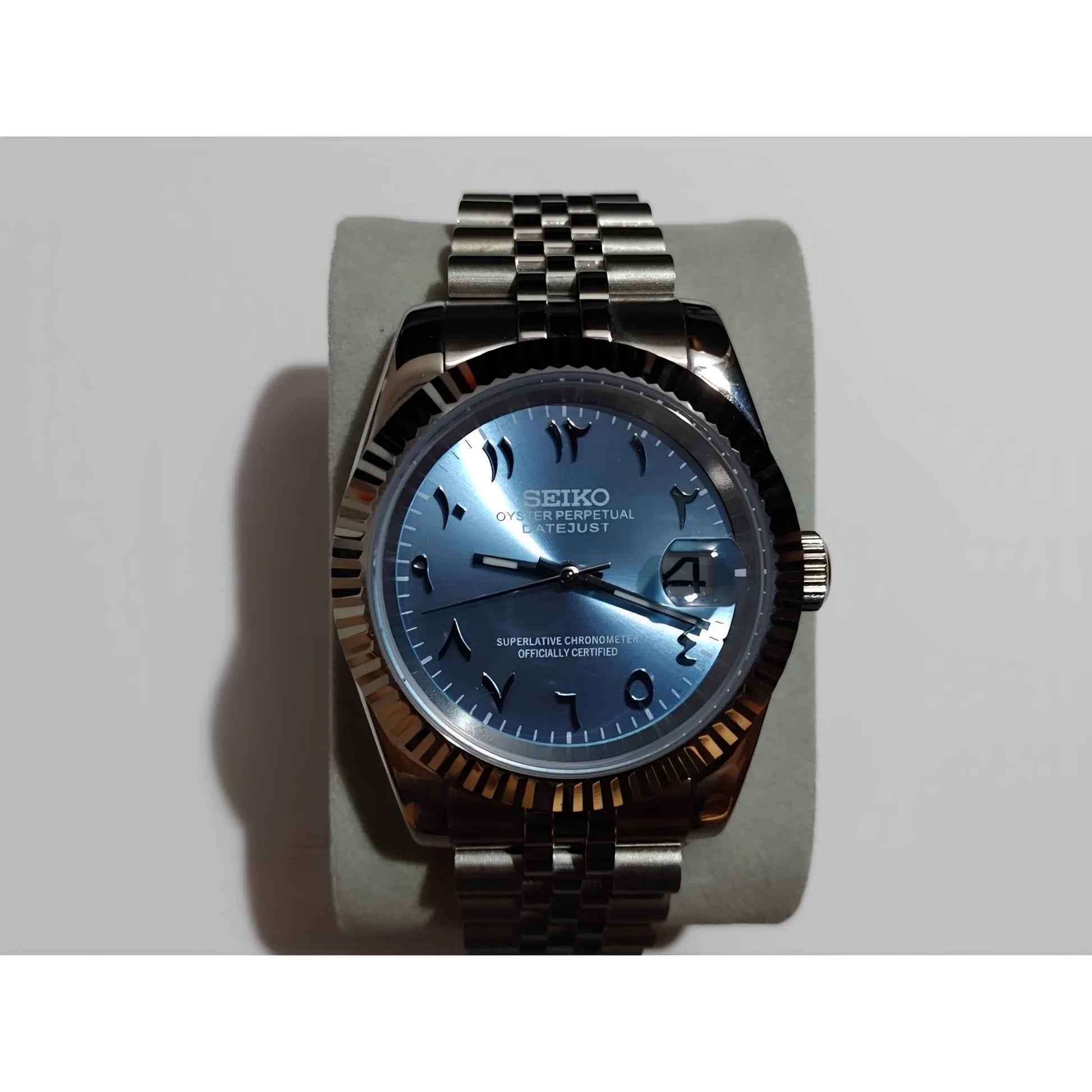 Seiko watch with ice blue dial, black Arabic numerals, chromed hour markers, date window, fluted bezel, and stainless steel.