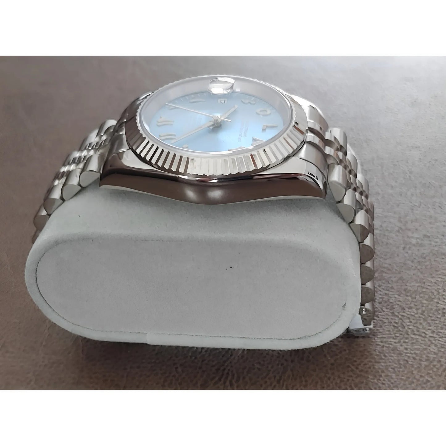 39mm stainless steel watch with fluted bezel, ice blue dial, chromed Arabic numerals, and metal link bracelet on gray.