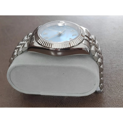 39mm stainless steel watch with fluted bezel, ice blue dial, chromed Arabic numerals, and metal link bracelet on gray.