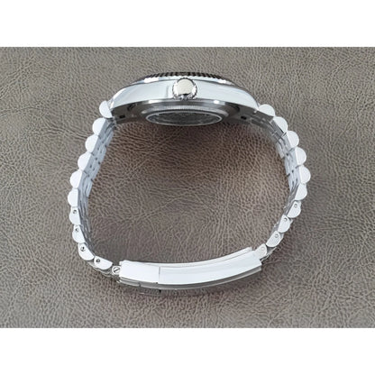 Silver stainless steel watch bracelet and case side with fluted bezel on brown textured surface.