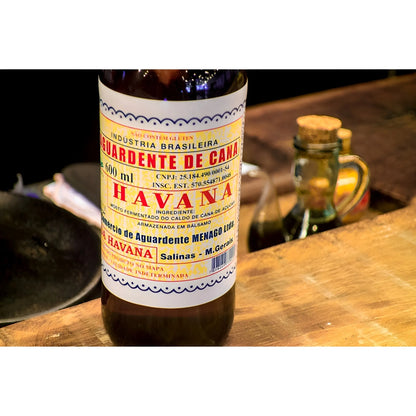 Glass bottle of Cachaca Havana 600ml with vintage-style label on wooden surface.