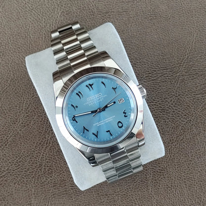 Seiko 39mm watch with ice blue dial, Arabic numerals, and polished stainless steel President bracelet.
