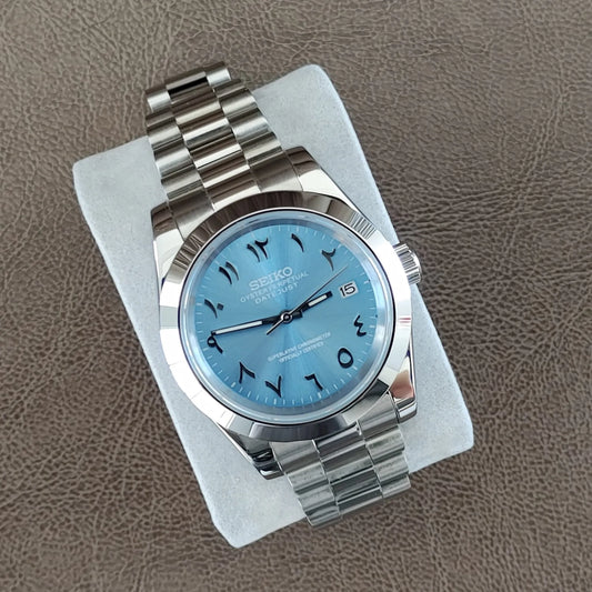 Seiko 39mm watch with ice blue dial, Arabic numerals, and polished stainless steel President bracelet.