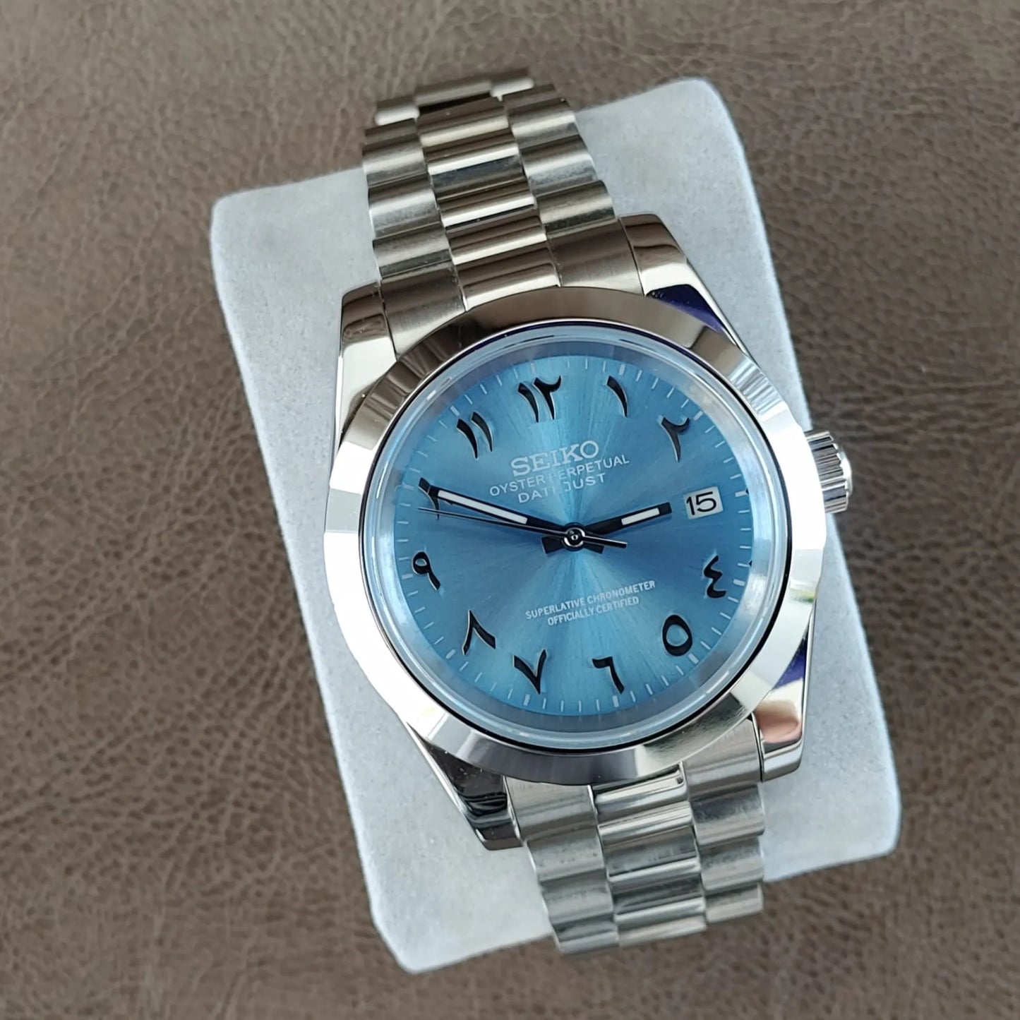 Stainless steel Seiko watch with 39mm polished case, ice blue dial, Arabic numerals, date window, and President bracelet.