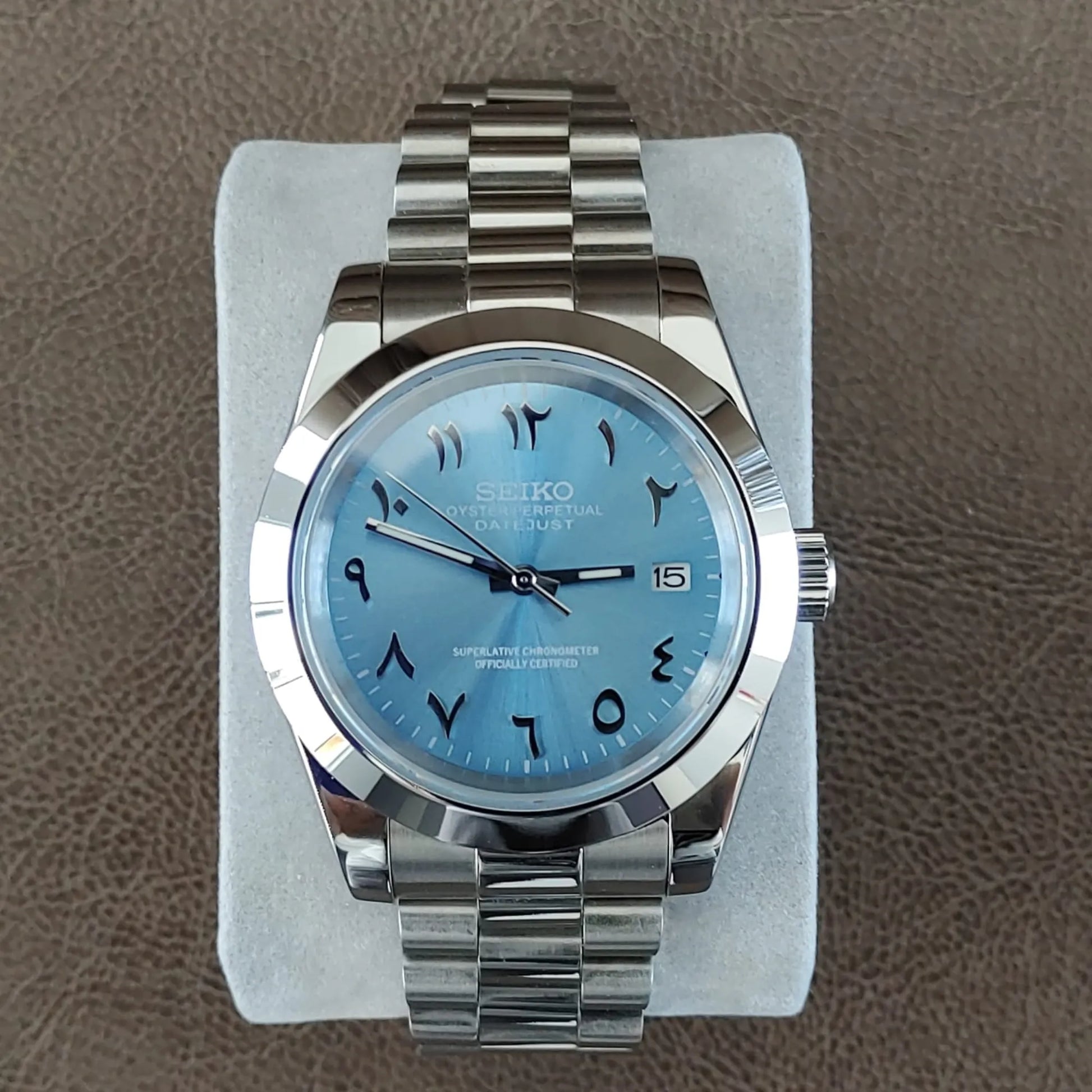 Seiko NH35 wristwatch with platinum case, fluted bezel, ice blue dial, Arabic numerals, and Jubilee bracelet.