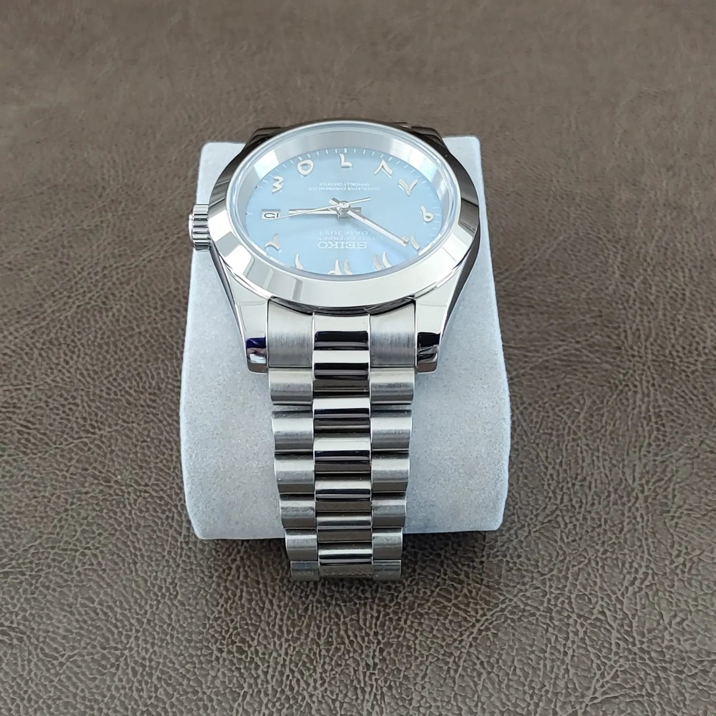 Seiko wristwatch with 39mm stainless steel case, ice blue dial, Arabic numerals, and silver President bracelet strap.