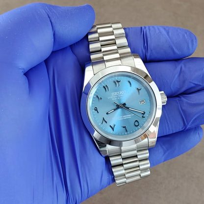 Seiko 39mm platinum watch with ice blue dial, Arabic numerals, fluted bezel, and Jubilee bracelet.