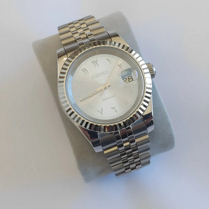 Seiko wristwatch with 39mm silver fluted bezel, ice blue dial, white Arabic numerals, and stainless steel jubilee bracelet.