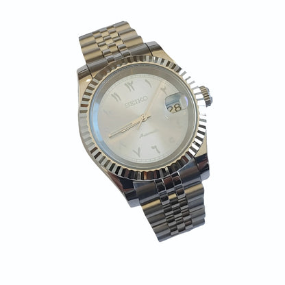 39mm silver stainless steel watch with fluted bezel, ice blue dial, white Arabic numerals, and date window at 3 o'clock.