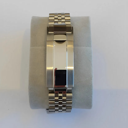 Silver stainless steel bracelet with polished fold-over clasp on grey cushion.