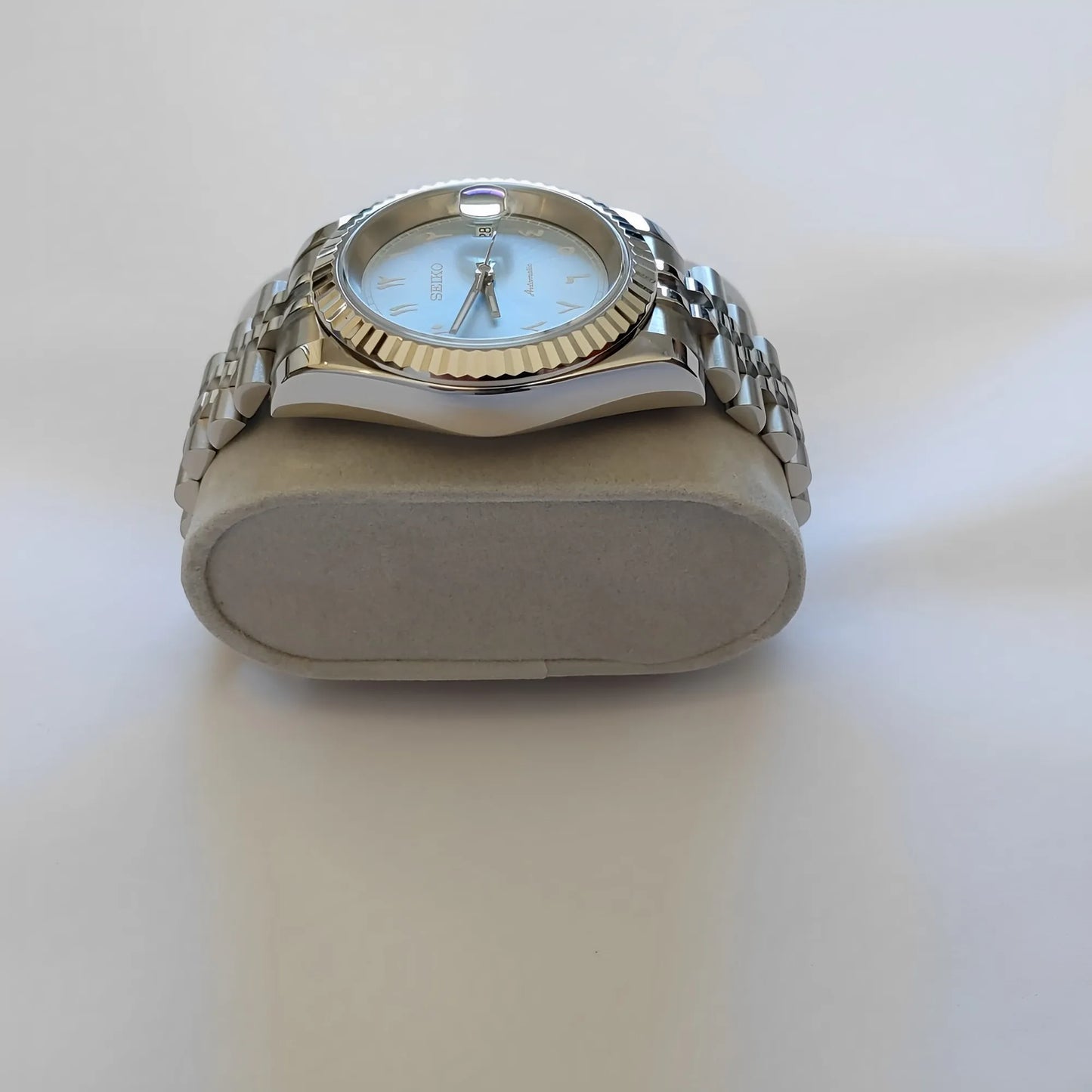 Seiko wristwatch with 39mm ice blue dial, white Arabic numerals, fluted silver bezel, and stainless steel bracelet.