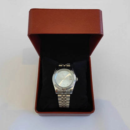 Silver metal wristwatch with fluted bezel, ice blue dial, white Arabic numerals, displayed in maroon leather box.