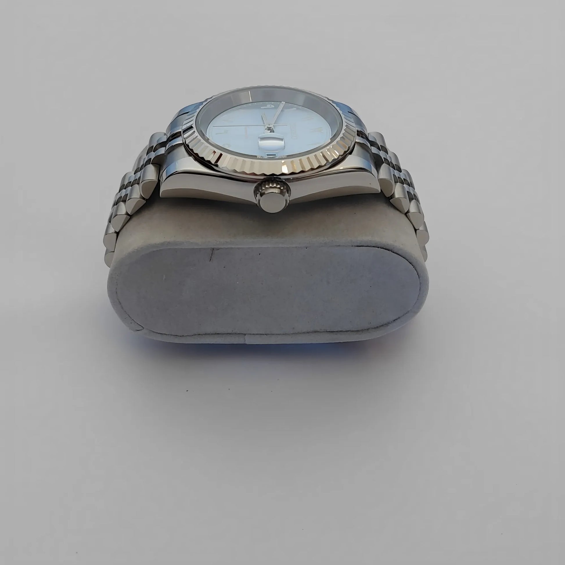 Silver stainless steel watch with fluted bezel, ice blue dial, white Arabic numerals, and linked bracelet strap.