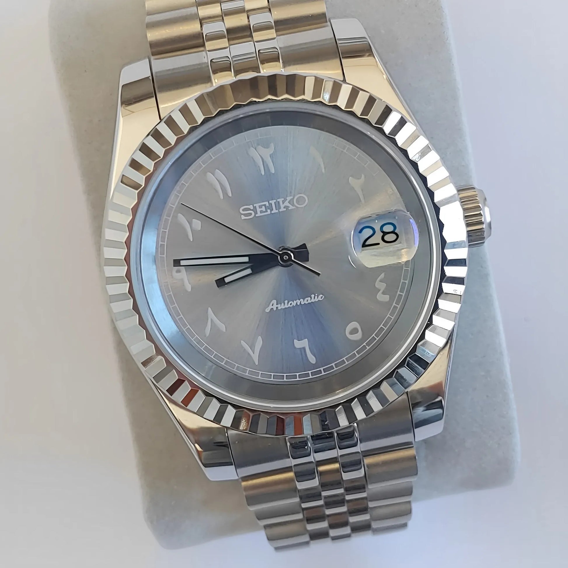 Seiko 39mm watch with ice blue Arabic dial, white indices, fluted bezel, and stainless steel bracelet.