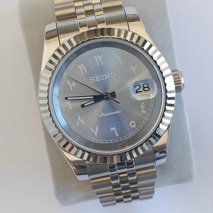 Seiko 39mm watch with ice blue Arabic dial, white indices, fluted bezel, and stainless steel bracelet.