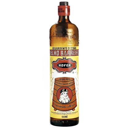 Tall amber glass bottle of Velho Barreiro with yellow label featuring a wooden barrel and red cap.