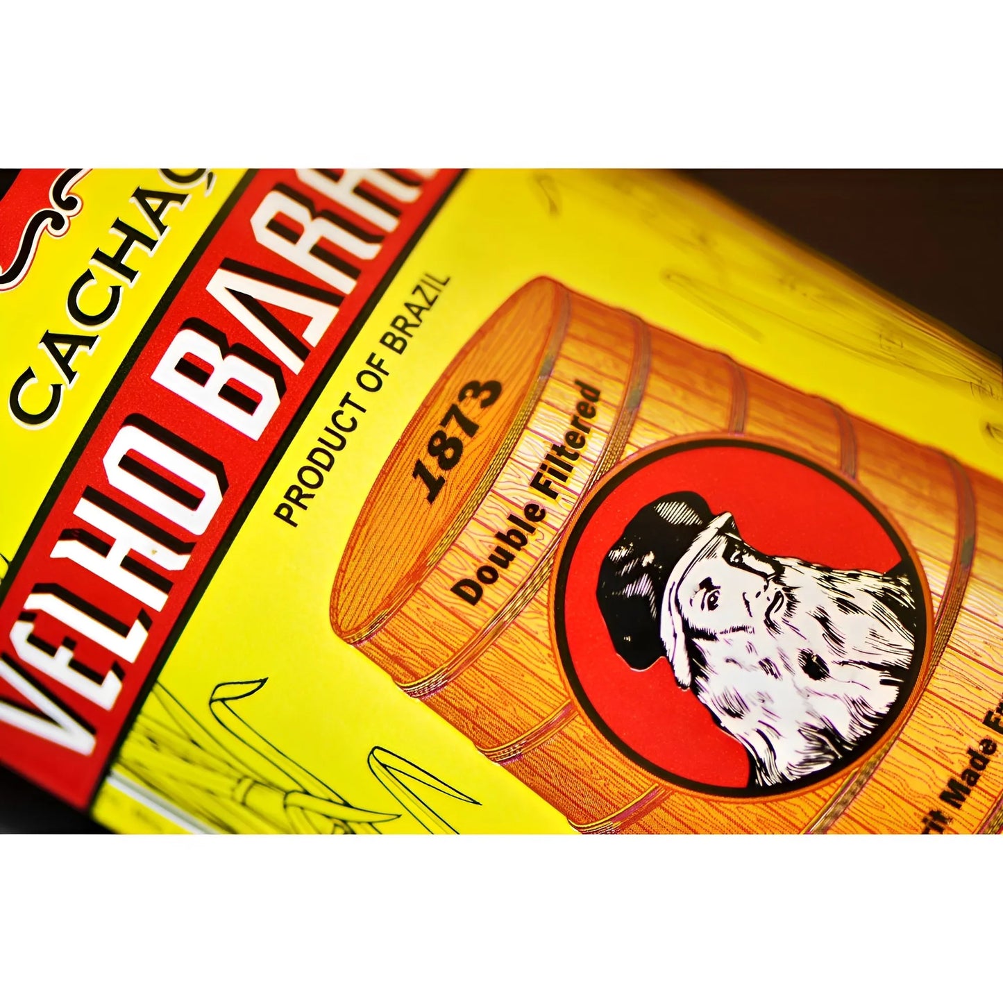 Yellow label with red and white Velho Barreiro text, barrel illustration, and bearded man logo on glass bottle.