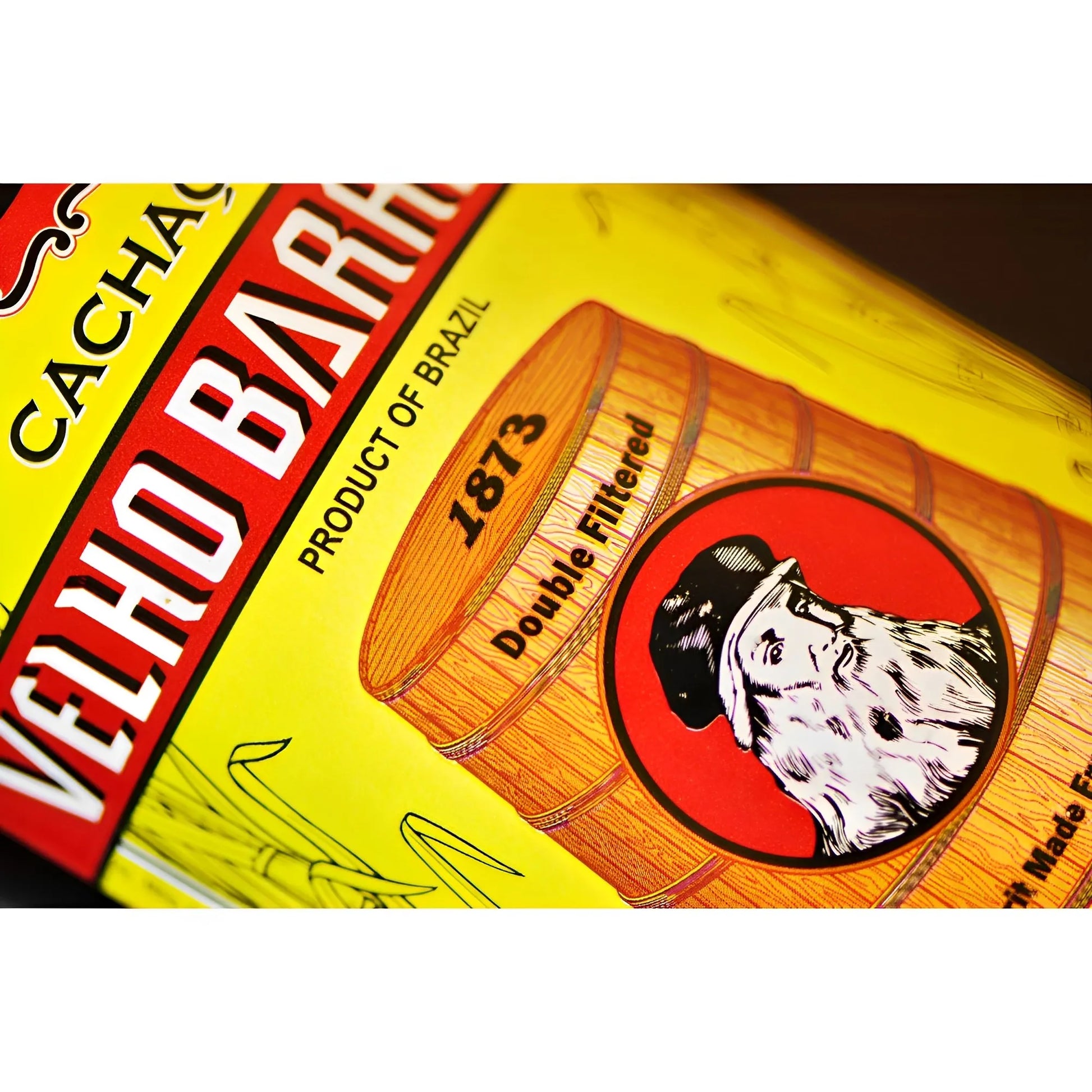 Yellow label with red and white Velho Barreiro text, barrel illustration, and bearded man logo on glass bottle.