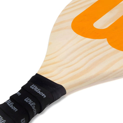 Wooden Wilson Frescobol paddle with light natural grain and large orange "W" logo, black grip wrapped handle.