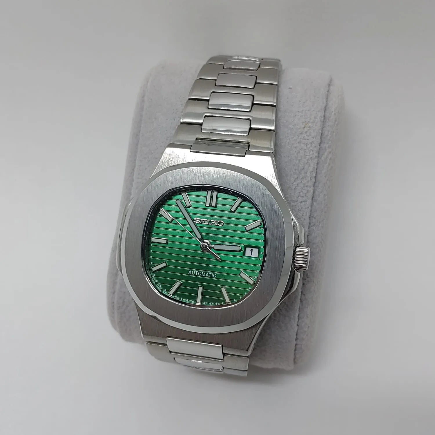 Stainless steel watch with green textured dial, silver hour markers, rectangular case, and metal bracelet.