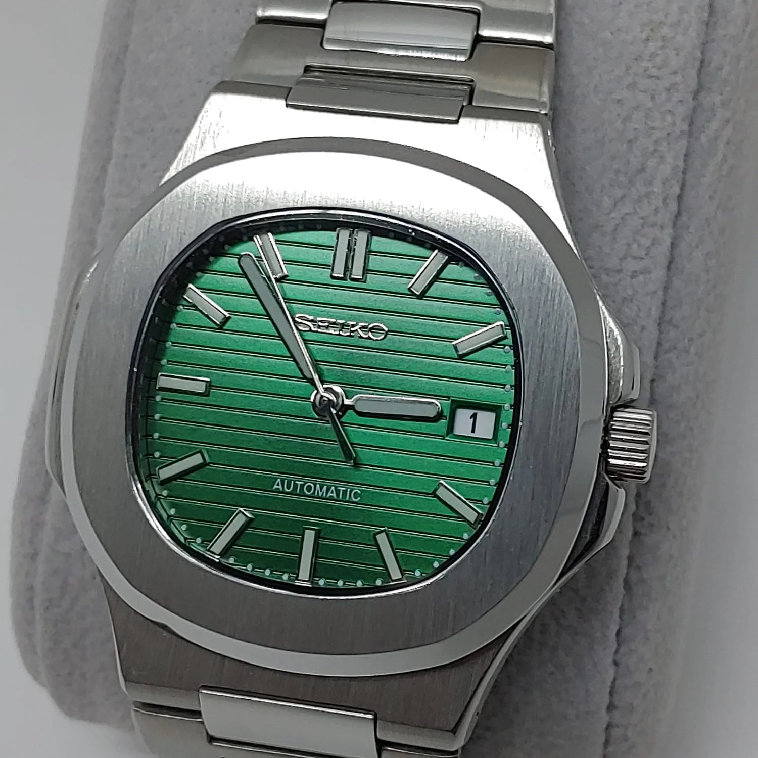 Seiko stainless steel watch with a green striped dial, silver hour markers, date window, and silver hands.