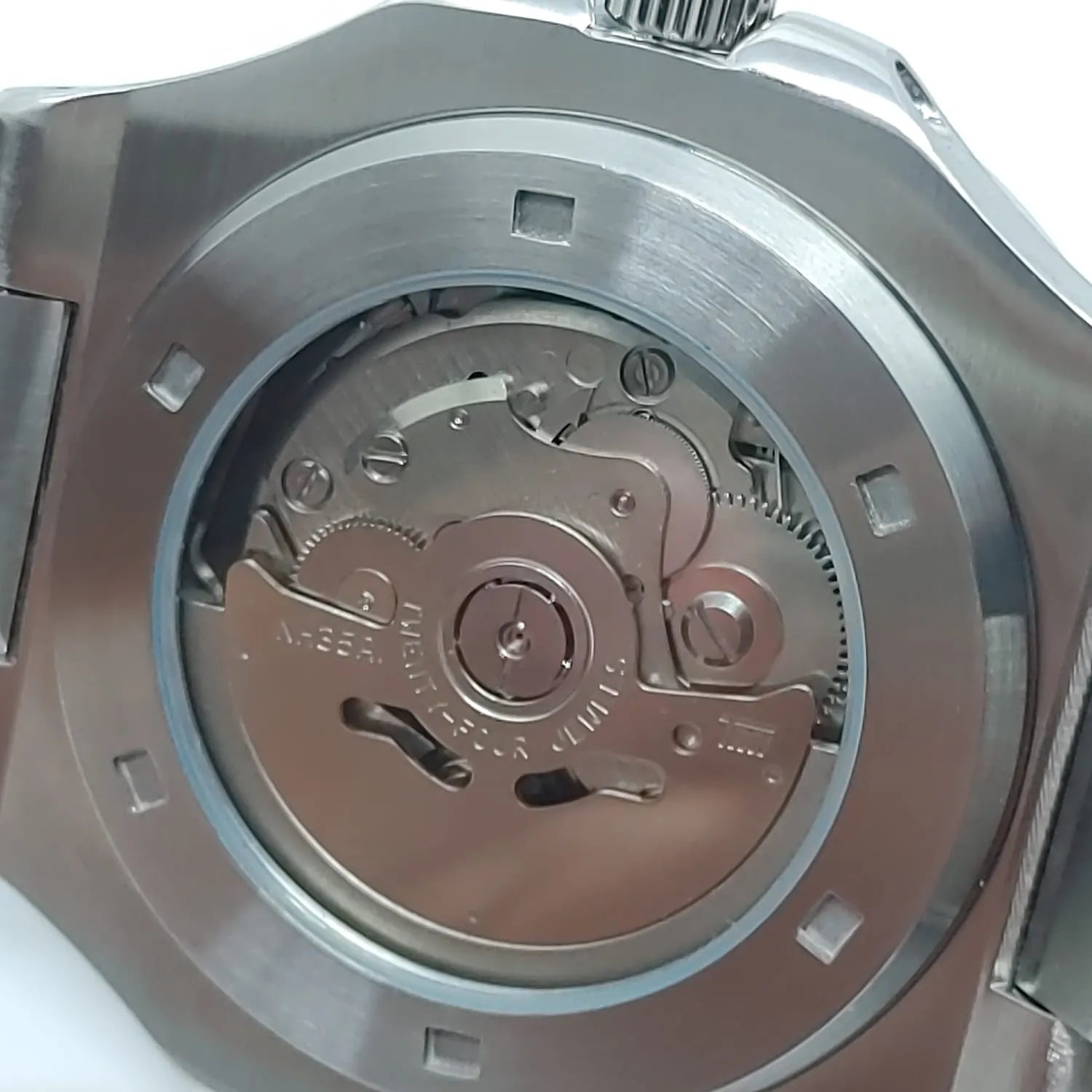 Close-up of Seiko NH35 watch's stainless steel case back showcasing the intricate automatic movement mechanism through a.