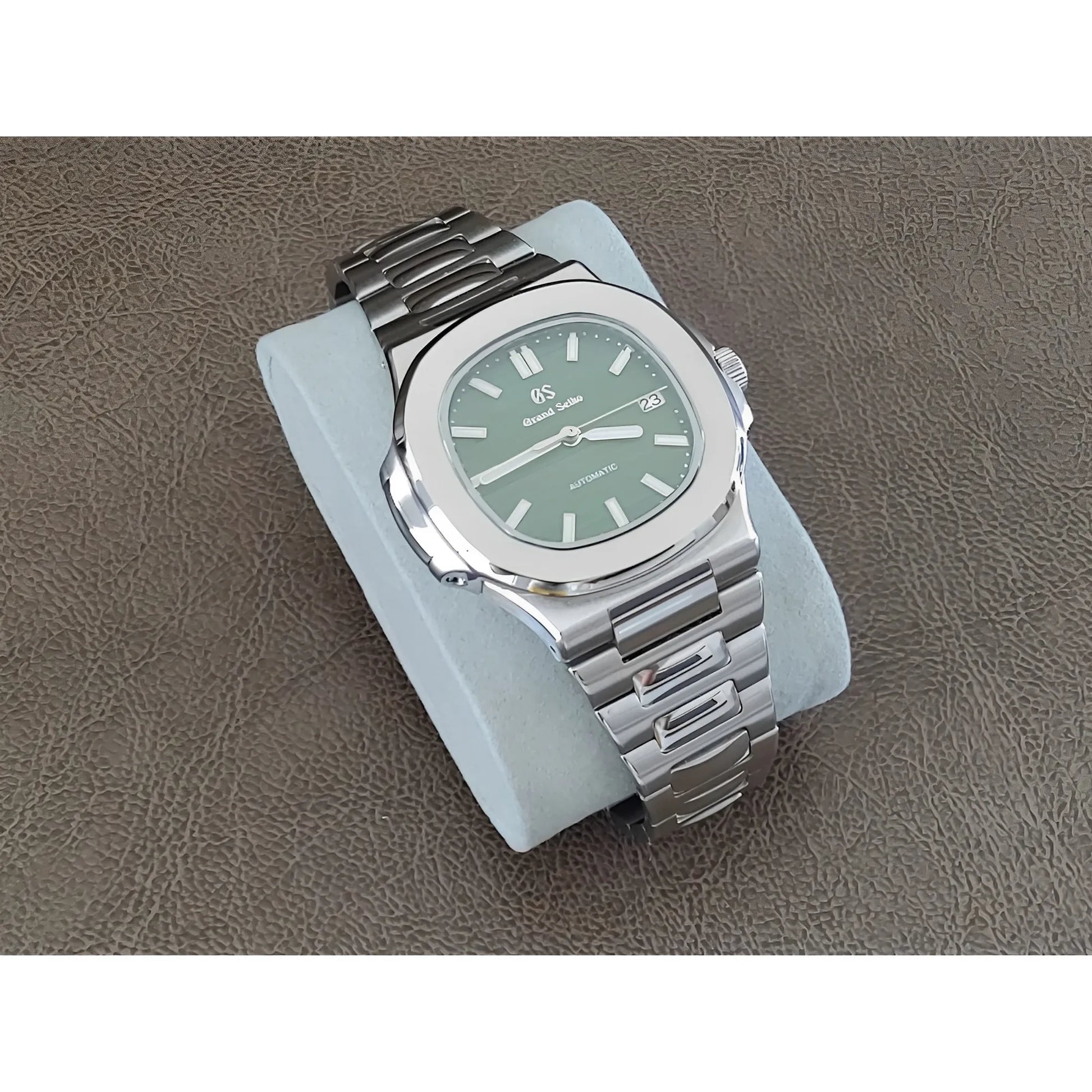 Stainless steel 40mm Seiko watch with olive green dial, silver hour markers, and bracelet strap on gray cushion.