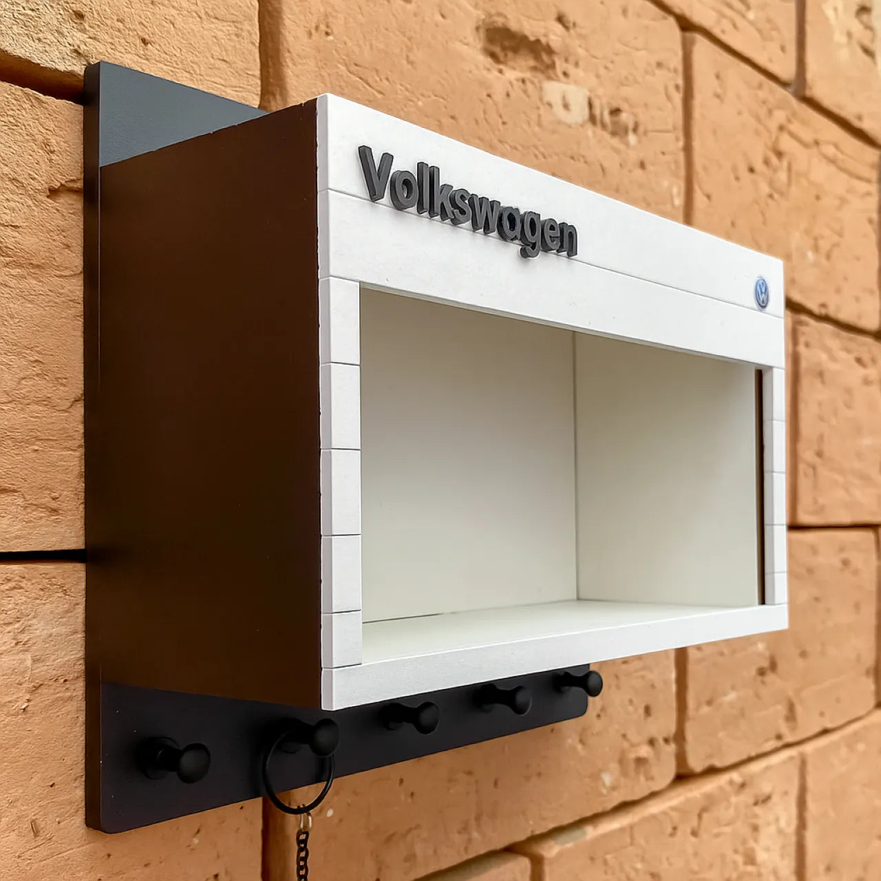 White and black Volkswagen wall-mounted key hook rack with scale model car display shelf.