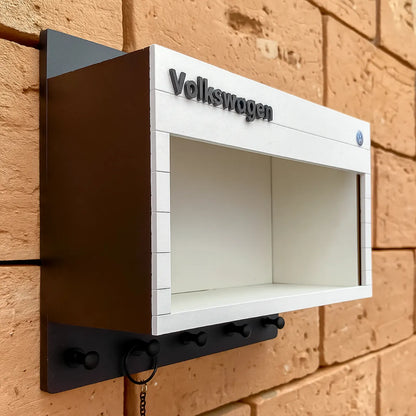 White and black Volkswagen wall-mounted key hook rack with scale model car display shelf.