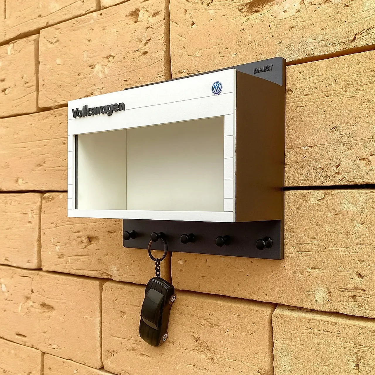 White and black Volkswagen wall-mounted key hook rack with open display shelf and four hooks, metal construction.