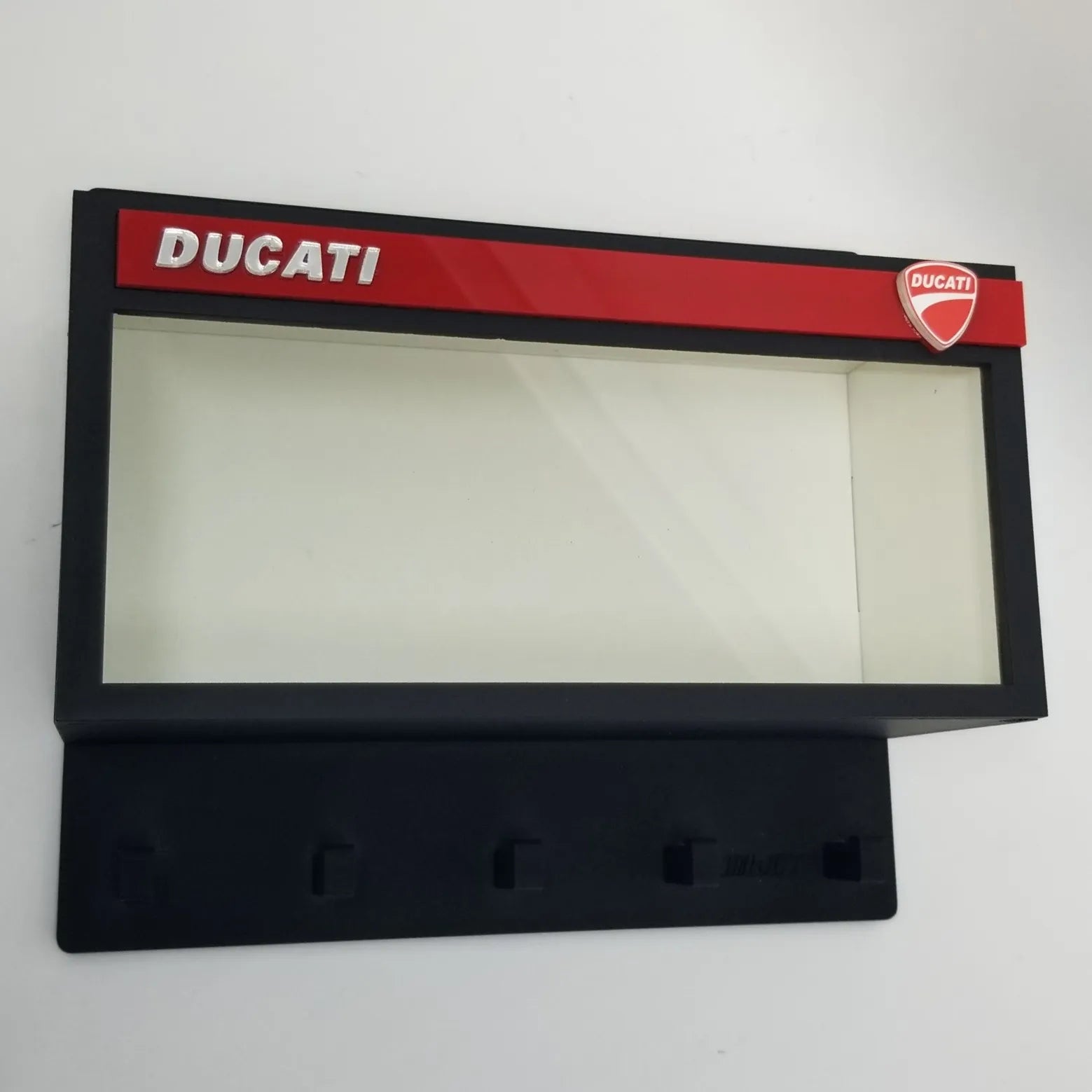 Black rectangular wall key hook rack with clear front display case, red Ducati logo accent, and four hooks underneath.