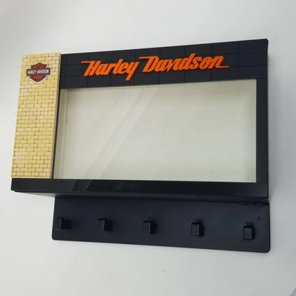 Black Harley Davidson wall key hook rack with orange logo and five hooks below a clear display case.