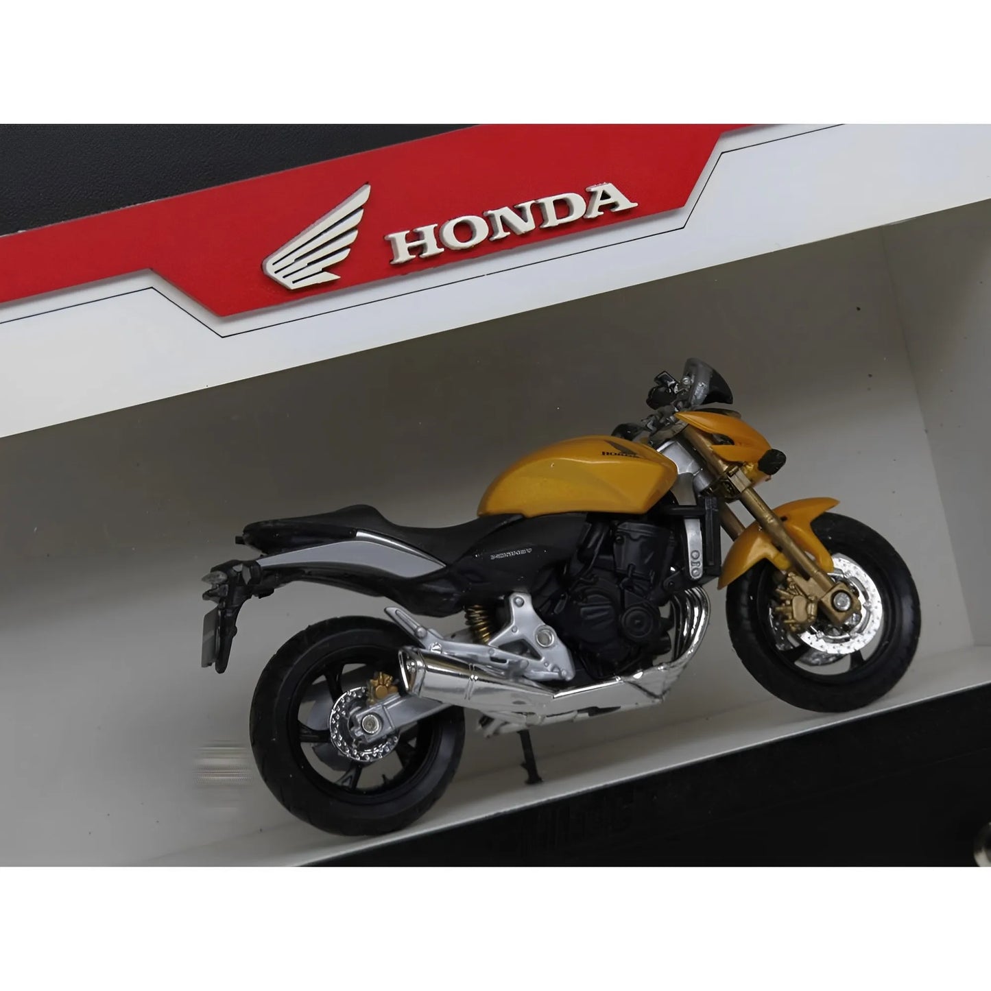 Yellow and black Honda motorcycle scale model mounted on a white wall key hook rack with red Honda branding.