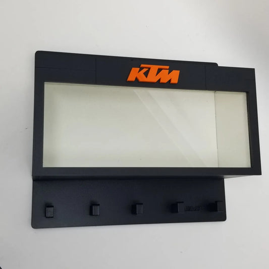 Black KTM wall key hook rack with orange KTM logo and five hooks below a glass display case.