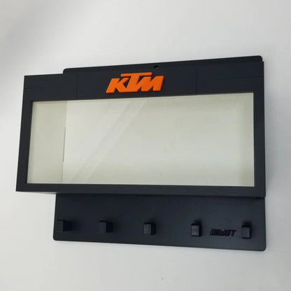 Black KTM wall key hook rack with orange logo and five hooks beneath a clear display case area.