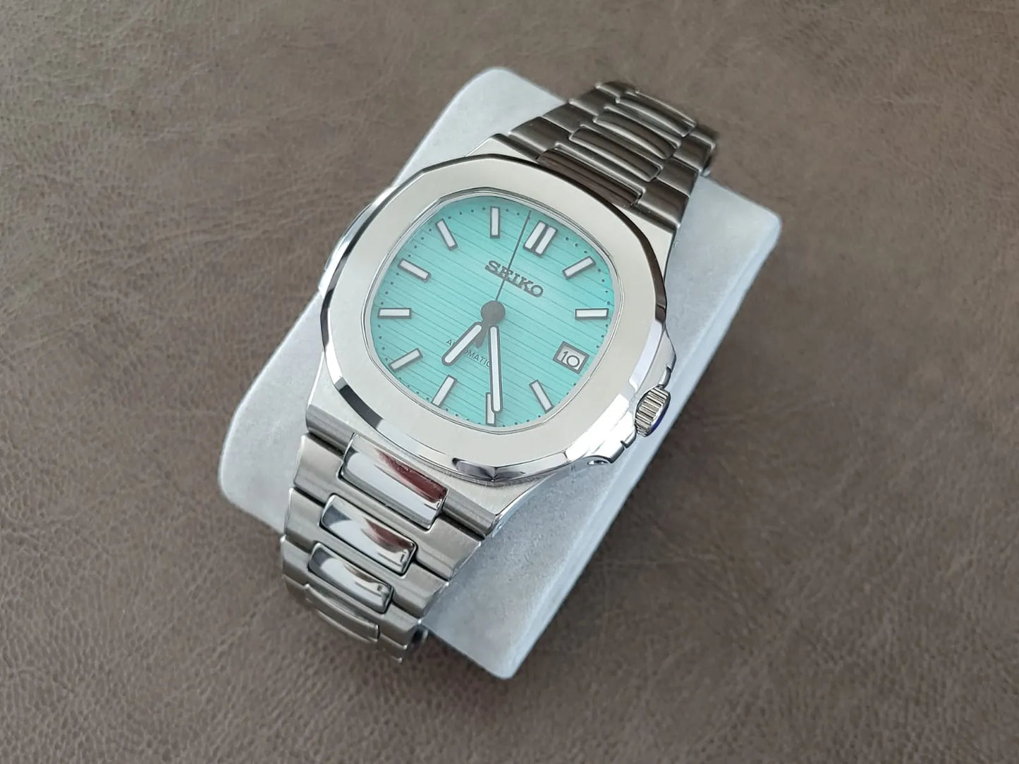 Stainless steel luxury watch with Tiffany green dial, silver hour markers, and link bracelet.