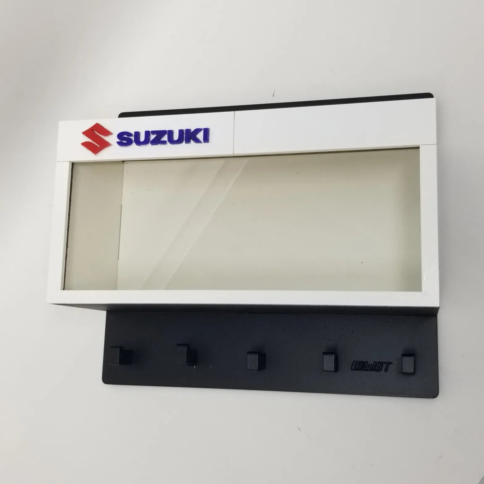 Suzuki wall-mounted key hook rack with white frame, clear display case, and five black hooks.