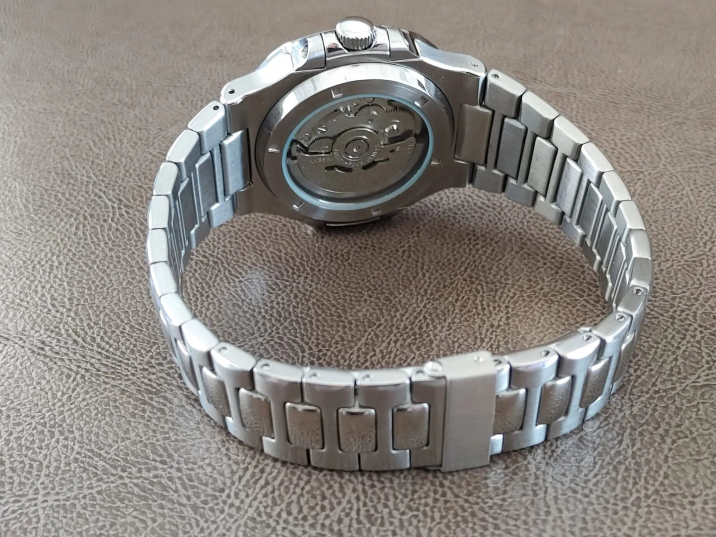 Seiko stainless steel watch with polished bracelet and transparent case back showing mechanical movement.
