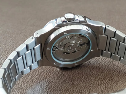 Stainless steel watch with visible automatic movement through transparent back case and linked metal bracelet.