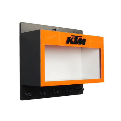 Black and orange KTM wall key hook rack with glass-front scale model motorcycle display case.