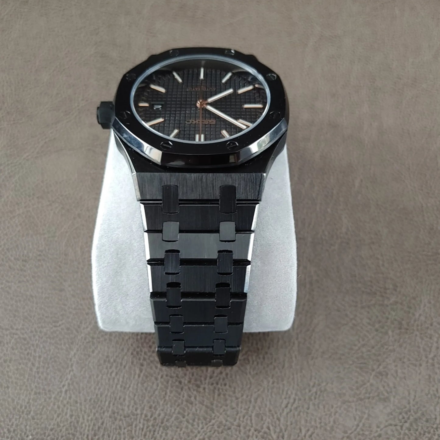 41mm black royal oak style watch with rose gold hands and hour markers, black metal bracelet.
