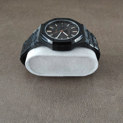 Black and rose gold wristwatch with octagonal bezel and metal link bracelet on white cushion.