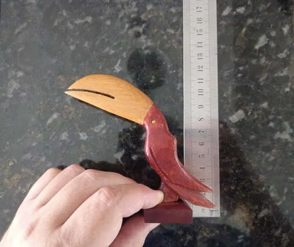 Small handcrafted wooden toucan sculpture with natural wood tones and smooth finish, standing on a rectangular base.