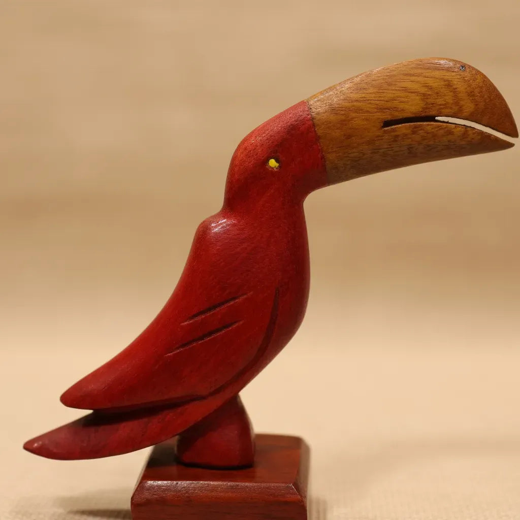 Handcrafted wooden toucan sculpture with red body, natural wood head, and yellow eye on square base.