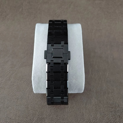Black stainless steel watch bracelet with polished and brushed links on white cushion display.