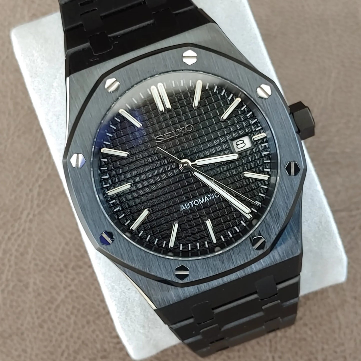 Black and silver Seiko NH35 Royal Oak watch with textured black dial, date window, and stainless steel bracelet.